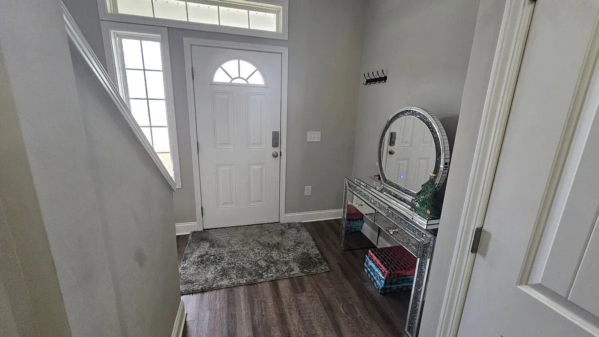 A welcoming entryway with a front door, mirrored console table, and area rug. The scene sets a tone of hospitality and warmth, reflecting the first impression guests receive and the private entrance mentioned in the section.