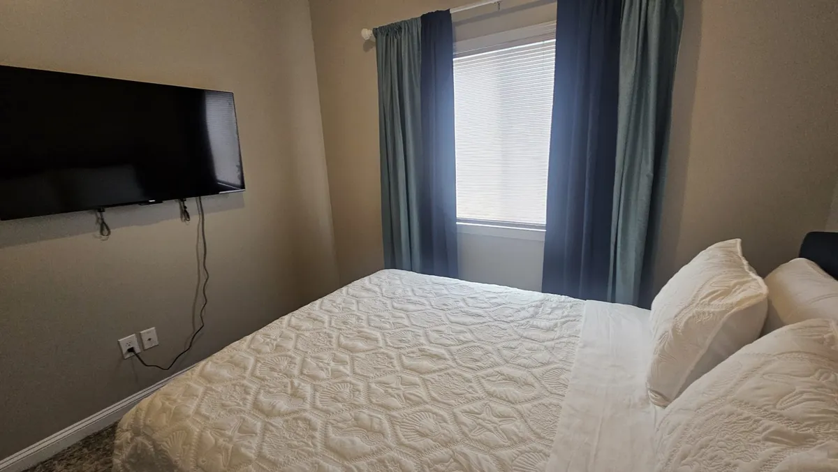 A relaxing bedroom with a comfortable bed, large window, and in-room TV. The space is designed for both rest and entertainment, with soft linens and a peaceful ambiance.