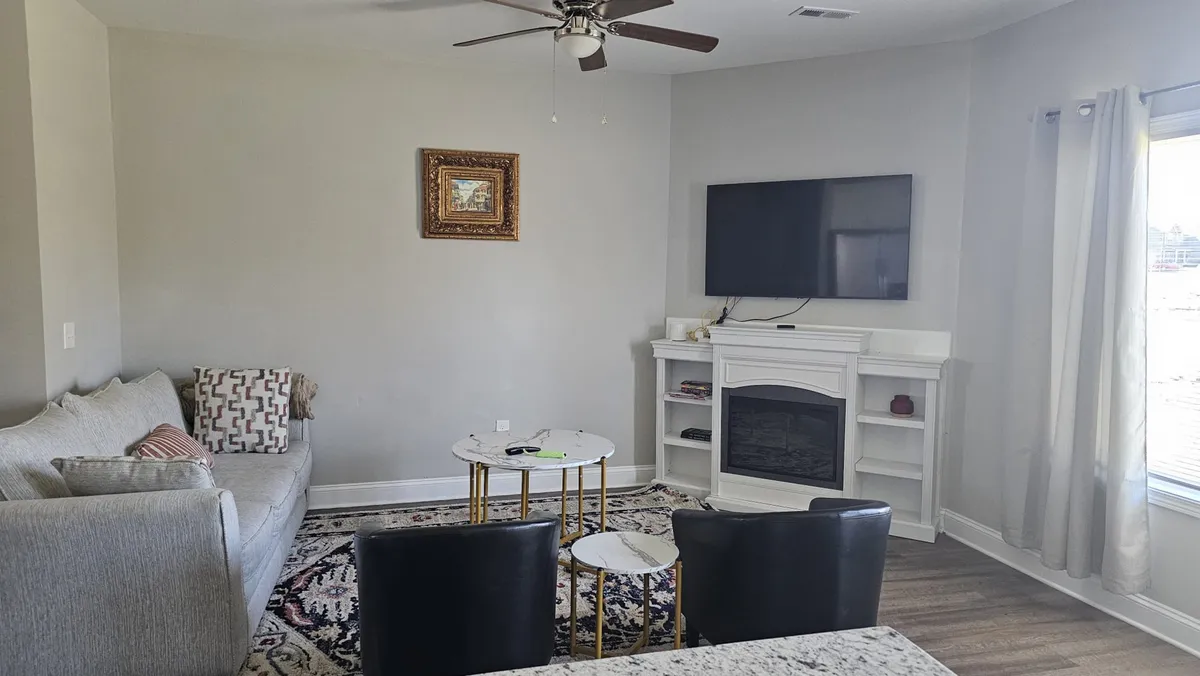 A cozy living room setup featuring a plush sofa, coffee table, TV, fireplace, and artwork. The arrangement invites relaxation and conversation, offering a comfortable spot for movie nights, socializing, or unwinding after a day out. The decor and soft textures highlight the sense of comfort and home.