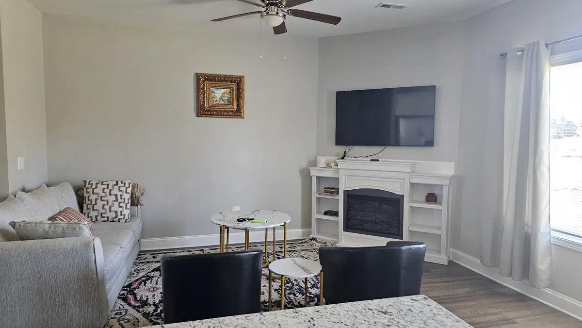 This image features a cozy living area with a sofa, coffee table, fireplace, television, and artwork. The scene suggests a welcoming space for relaxing, socializing, or winding down after a day out.